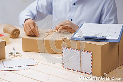 Courier making notes in delivery receipt among parcels at table Stock Photo