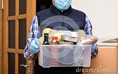 Courier in protective medical mask and gloves deliver products in plastic box Stock Photo