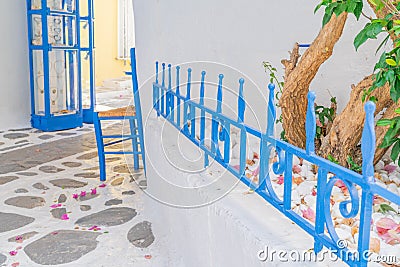 Courtyard with blue wrought iron fence, blue chair and crazy paving and pink bougainvillea petals Stock Photo