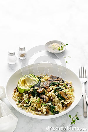 Couscous with avocado, spinach and sauteed champignon mushrooms with onion Stock Photo