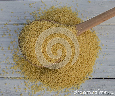 Couscous grain in a wooden spoon Stock Photo