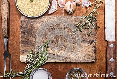 Couscous herb knife meat fork garlic and salt seasoning cutting board. Ingredients wooden rustic background close up top view Stock Photo