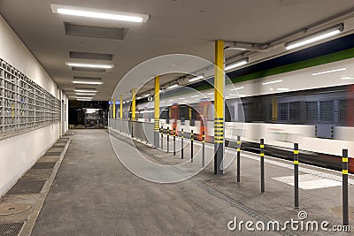 Covered station platform illuminated by led lights. The train passes by at full speed Stock Photo