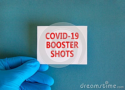 Covid-19 booster shots vaccine symbol. White note with words Covid-19 booster shots, beautiful blue background, doctor hand in Stock Photo