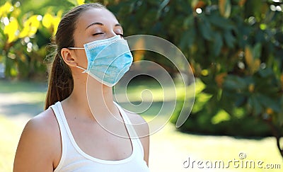 COVID-19 Close up of young sporty woman with surgical mask breathing in the park Stock Photo