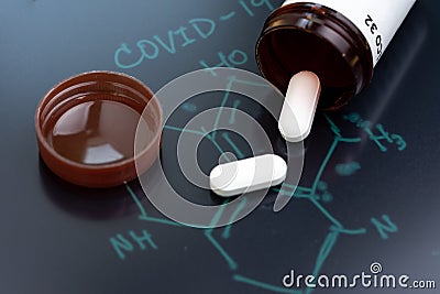 COVID-19, Corona virus flu dose of medicine or treatment drug concept, white pill tablet from medicine bottle on chemical compound Stock Photo