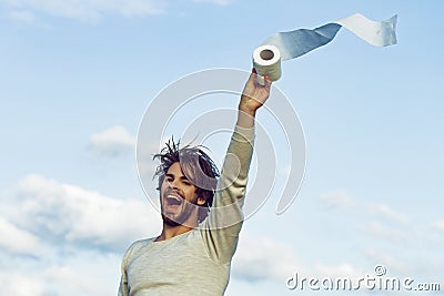 Covid, corona virus. WC and restroom. Sterility and purity. Man with happy face hold toilet paper on blue sky. Hygiene Stock Photo