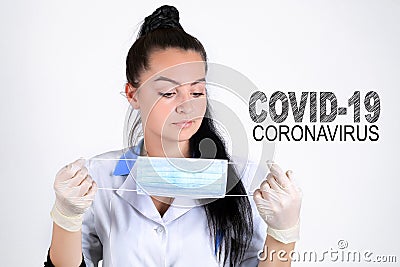 Covid-19 coronavirus desease global pandemic outbreak. A young female doctor in a medical mask with lettering. Close up portrait f Stock Photo