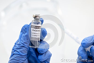 COVID-19 coronavirus vaccine in doctor gloved hand, syringe and vaccine bottle for injection Stock Photo