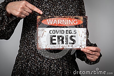 Covid EG.5 ERIS. A woman is holding a warning sign with text Stock Photo
