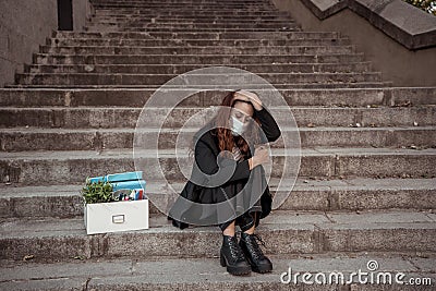 Sad woman in face mask with office box feeling hopeless after losing job due to coronavirus job cuts Stock Photo