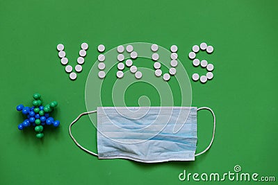 Inscription VIRUS from white pills on green background with mask medical Stock Photo