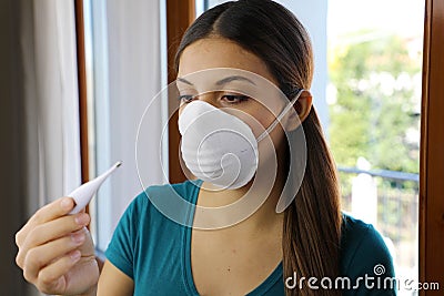 COVID-19 Pandemic Coronavirus Mask Fever Worry Woman Checking Temperature with Thermometer at Home Symptom of SARS-CoV-2. Girl Stock Photo