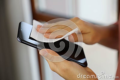 COVID-19 Pandemic Coronavirus Woman disinfecting cleaning mobile phone screen preventive wiping for SARS-CoV-2 Coronavirus disease Stock Photo