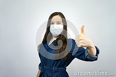 Covid19, quarantine. Happy girl show thumbs up in medical face mask. stay safe during coronavirus outbreak Stock Photo