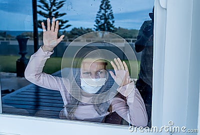 COVID-19 Quarantine. Sad little girl looking through the window feeling lonely during lockdown Stock Photo