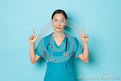 Covid-19, social distancing and coronavirus pandemic concept. Skeptical and doubtful young asian female doctor Stock Photo