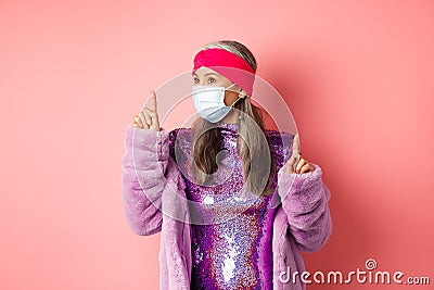 Covid-19, social distancing and fashion concept. Fancy asian senior woman dancing and having fun, wearing medical Stock Photo