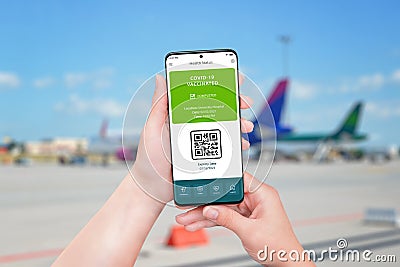 Covid vaccination passport on smart phone. Airport with planes in background Stock Photo