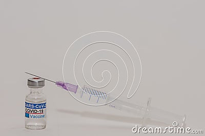 Covid vaccine in a bottle right gray background with a syringe complete view Stock Photo