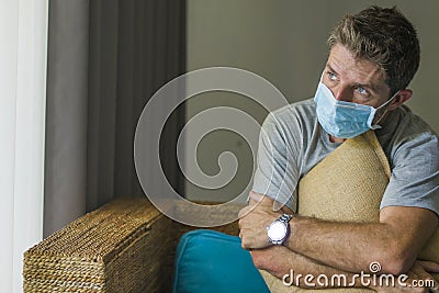 Covid-19 virus lockdown - sad and worried man in medical mask thinking and feeling scared in quarantine following stay at home Stock Photo