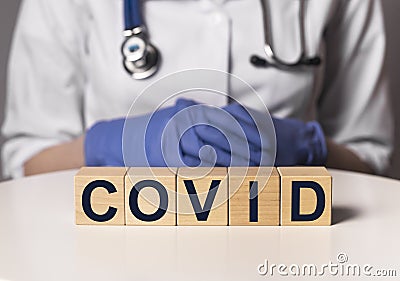 Covid word, inscription on wooden dices in doctor hands Stock Photo