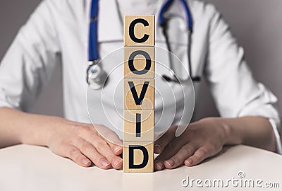 Covid word, inscription on wooden dices in doctor hands Stock Photo