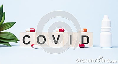 COVID word made with building blocks. A row of wooden cubes with a word written in black font is located on white background Stock Photo