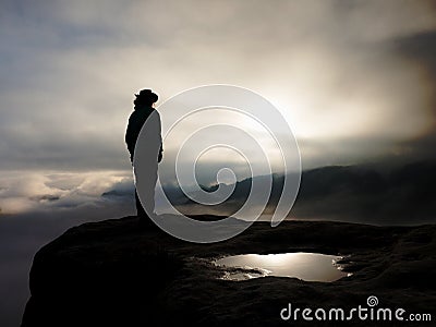 Cow girl in cowboy hat on mountain peak look into heavy mist Stock Photo