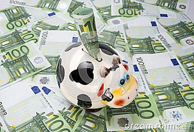 Cow a moneybox on a green field of euro notes Stock Photo