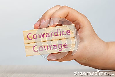 Cowardice and Courage. A hand holds two wooden cubes with the inscriptions COWARDICE and COURAGE close-up For insertion Stock Photo