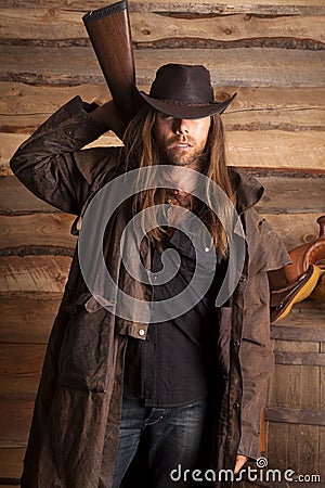 Cowboy duster long hair rifle behind back Stock Photo