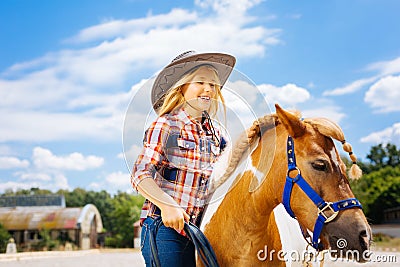 Cute smiling cowboy girl leading little beautiful pony Stock Photo