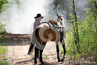 Cowboy on his horse walking through dust in the forest Stock Photo