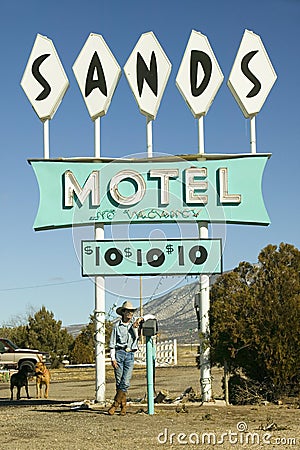 Cowboy leans against post in front of Sands Motel sign with RV Parking for $10, at the intersection of Route 54 & 380 in Editorial Stock Photo