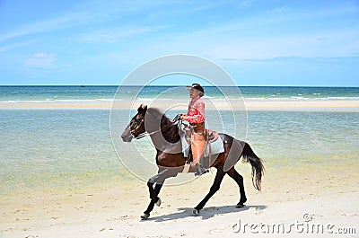 Cowboy is riding Horse walk on the beach Stock Photo