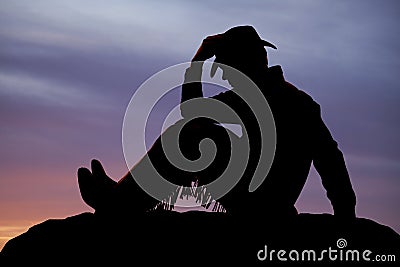 Cowboy sit sunset hold hat Stock Photo