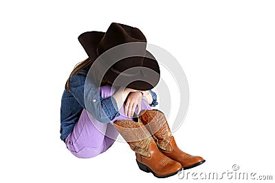 Cowgirl sitting and sulking with her head down on her knees Stock Photo