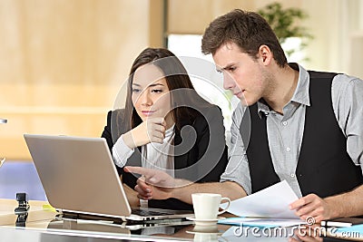 Coworkers checking laptop content together at office Stock Photo