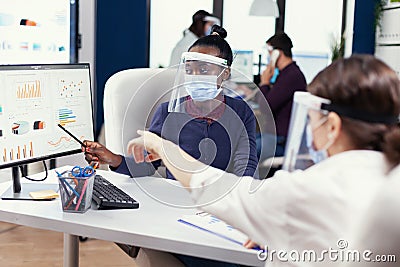 Coworkers in office pointing at financial graph Stock Photo