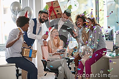 Coworkers surprising female colleague with birthday cake at work in office. surprise, birthday party at work Stock Photo