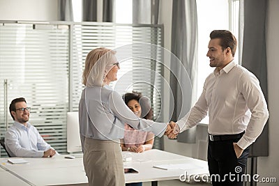 In coworking middle aged boss greeting new employee with handshake Stock Photo