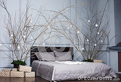 Coziness, comfort, interior and holidays concept - cozy bedroom with bed and christmas garland lights at home Stock Photo