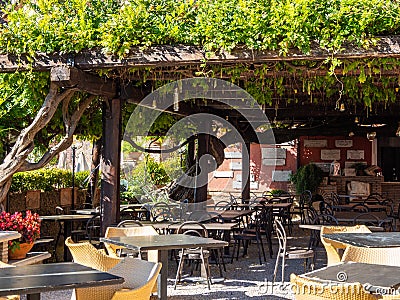 A cozy cafe under a lively green canopy on the banks of the River Aniene in Tivoli, Italy Stock Photo