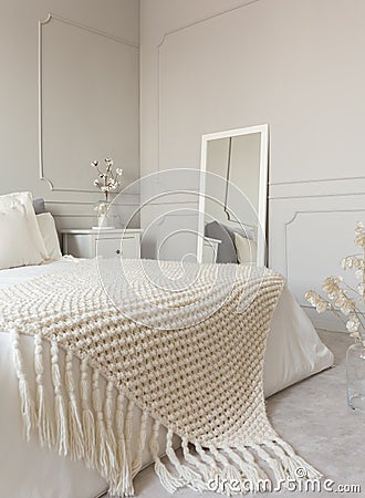 Cozy cream colored woolen blanket on king size bed in bright bedroom Stock Photo