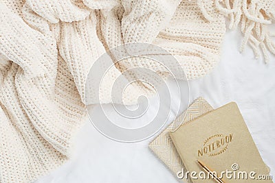 Cozy cream blanket on white bed flatlay with neutral notebooks and gold pen Stock Photo