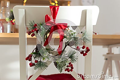 Cozy decorated with Christmas decorations with red ribbon and fir branches white kitchen chair Stock Photo