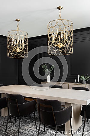 A black dining room with wainscoting walls and gold chandelier. Stock Photo