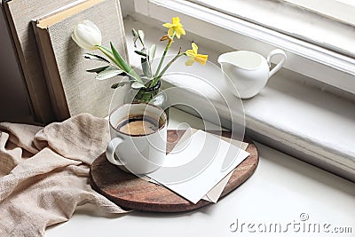 Cozy Easter spring still life. Greeting card mockup scene. Cup of coffee, books, wooden cutting board, milk pitcher and Stock Photo