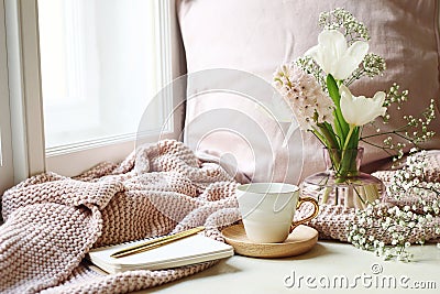 Cozy Easter, spring still life scene. Cup of coffee, opened notebook, pink knitted plaid on windowsill. Vintage feminine Stock Photo